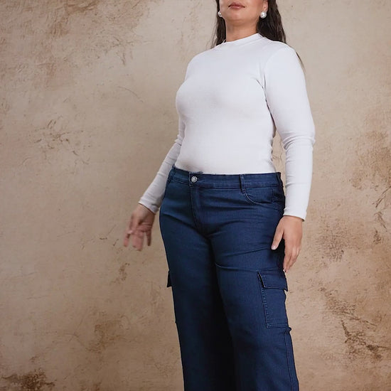 Plus size woman showcasing Curvisha buttoned blue denim pants with functional side pockets and premium stitching.