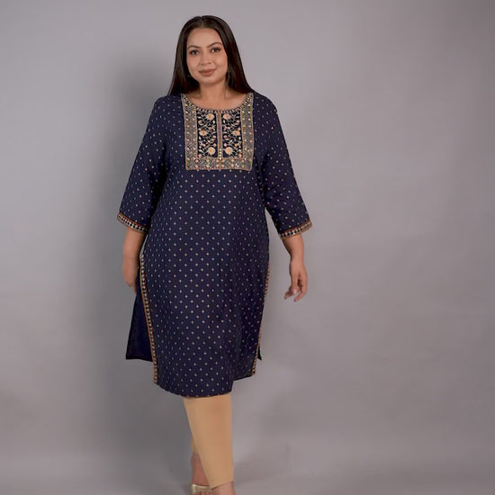 A plus-size model showcasing a Curvisha navy blue ethnic kurta with gold foil print and intricate yoke embroidery, paired with beige leggings.