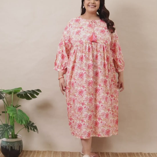 Plus-size pink and white floral tiered dress by Curvisha with boho-style bell sleeves and tassel neck detail.