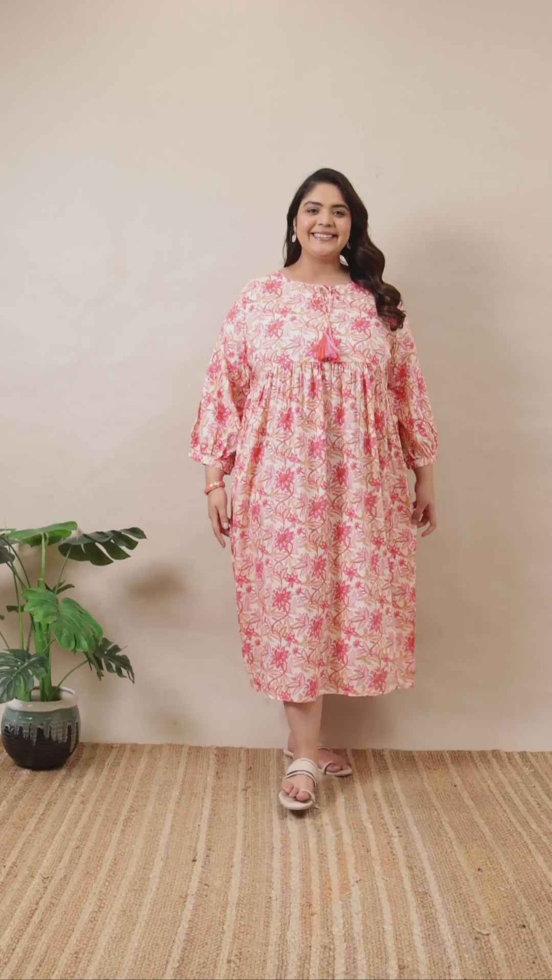 Plus-size pink and white floral tiered dress by Curvisha with boho-style bell sleeves and tassel neck detail.
