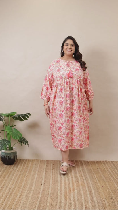 Plus-size pink and white floral tiered dress by Curvisha with boho-style bell sleeves and tassel neck detail.