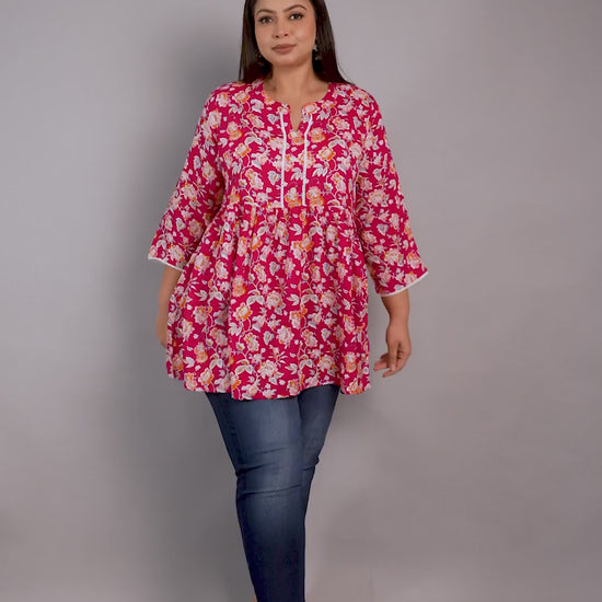 Curvisha plus-size pink and orange floral print peplum tunic featuring lace details and a tie-up neck, paired with blue jeans.