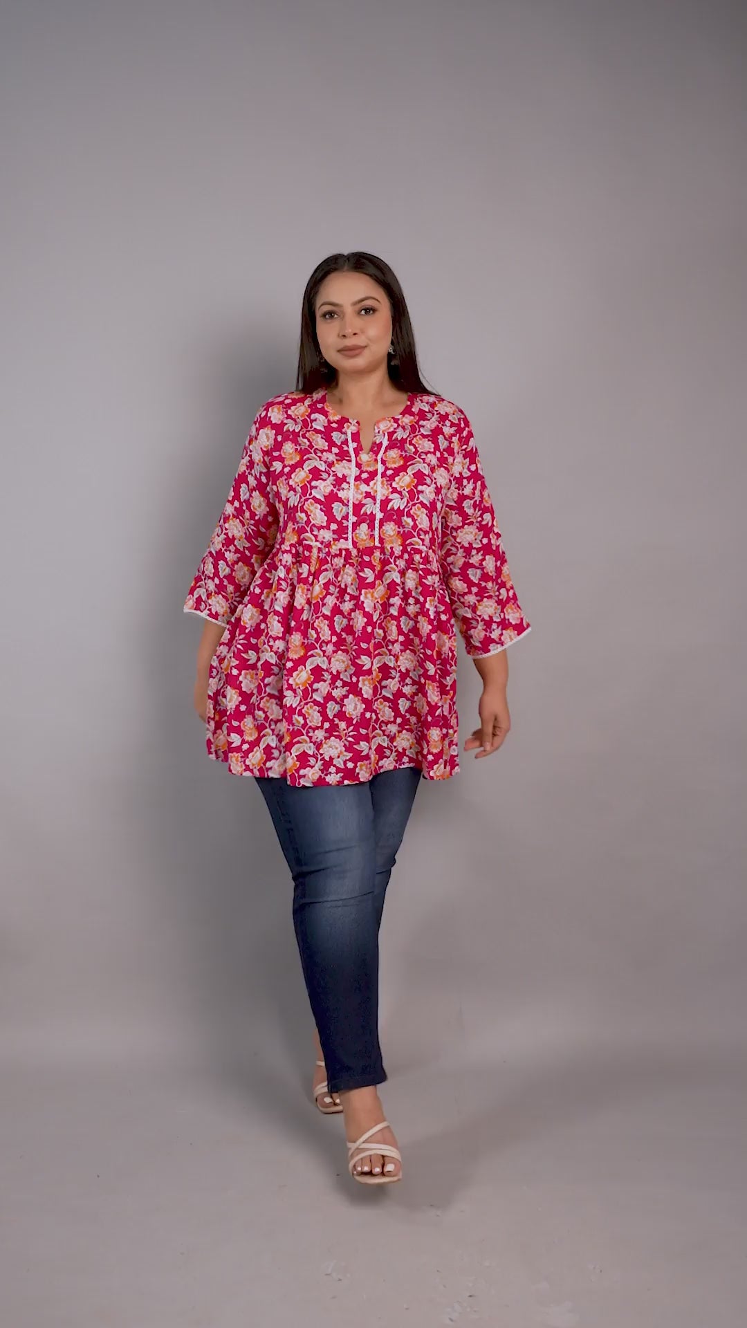 Curvisha plus-size pink and orange floral print peplum tunic featuring lace details and a tie-up neck, paired with blue jeans.
