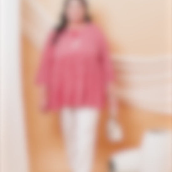 Plus size woman wearing a Curvisha pink and white Bandhani print cotton tunic with 3/4 sleeves and white trousers.